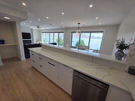 Una cocina moderna con encimera de mármol, lavavajillas integrado y grandes ventanales con vistas al lago.
