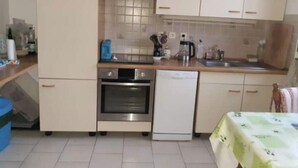 A compact kitchen with a dishwasher, oven, and a coffee maker on the counter.