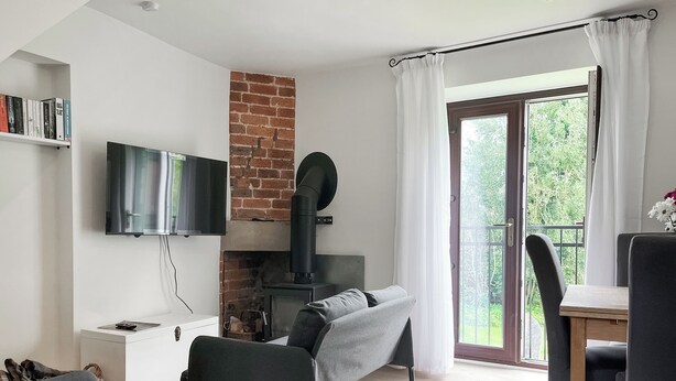 A modern living room with a fireplace, a sofa, a TV, and a dining area with chairs.