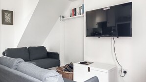 A modern living room with a grey sofa, a white sideboard, and a mounted TV.