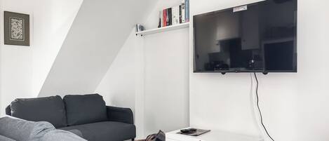 A modern living room with a grey sofa, a white sideboard, and a mounted TV.