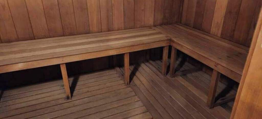 A wooden bench in a sauna room with a wooden floor.