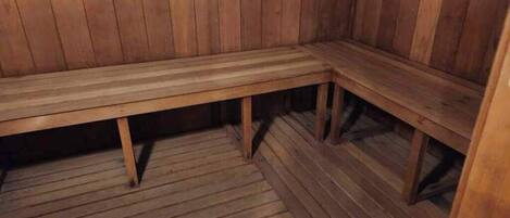 A wooden bench in a sauna room with a wooden floor.