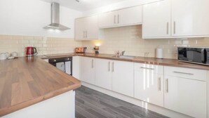 A modern kitchen with white cabinets, a wooden countertop, and a stainless steel range hood. - Stylish 5 Bed Flat in Thornaby, Ideal for Groups (Thornaby)