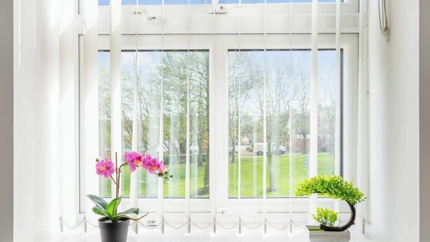 A window with white blinds, two potted plants, and a view of a green landscape. - Stylish 5 Bed Flat in Thornaby, Ideal for Groups (Thornaby)