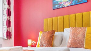 A hotel room with a vibrant red wall, a yellow headboard, and patterned pillows. - Stylish 5 Bed Flat in Thornaby, Ideal for Groups (Thornaby)