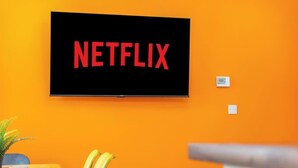 A television mounted on an orange wall with the Netflix logo. - Stylish 5 Bed Flat in Thornaby, Ideal for Groups (Thornaby)