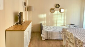 Ein gemütlicher Raum mit einem Holztisch, einem Bett mit gestreifter Bettwäsche und einem Esstisch mit Stühlen.