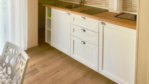 Eine kleine Küche mit weißen Schränken, einer Holz Arbeitsplatte und einem Edelstahl-Spülbecken.