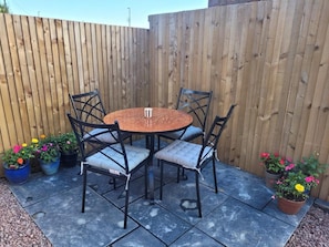 A round wooden table with four chairs, surrounded by potted plants. - Forest Cedar Lodge, Cinderford, Sleeps 4 (Cinderford)