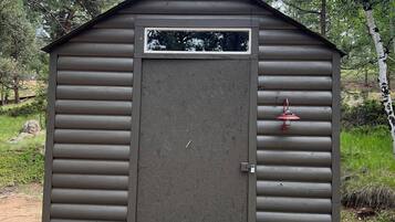A small, single-story wooden shed with a closed door and a window.