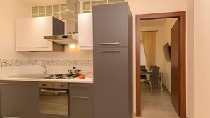 A modern kitchen with grey cabinets, a gas stove, and a microwave. - Il Giardino Degli Agrumi - Roma (Roma)