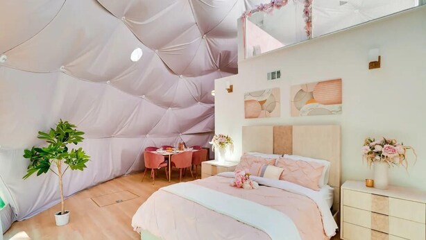 Een slaapkamer met een bed, nachtkastje en een eettafel met stoelen.