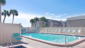 A swimming pool with multiple lanes, lounge chairs, and palm trees. - Ocean Front Condo Downtown Cocoa Beach (Cocoa Beach)