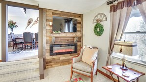 Una sala de estar con chimenea, un comedor con sillas y vistas al exterior.