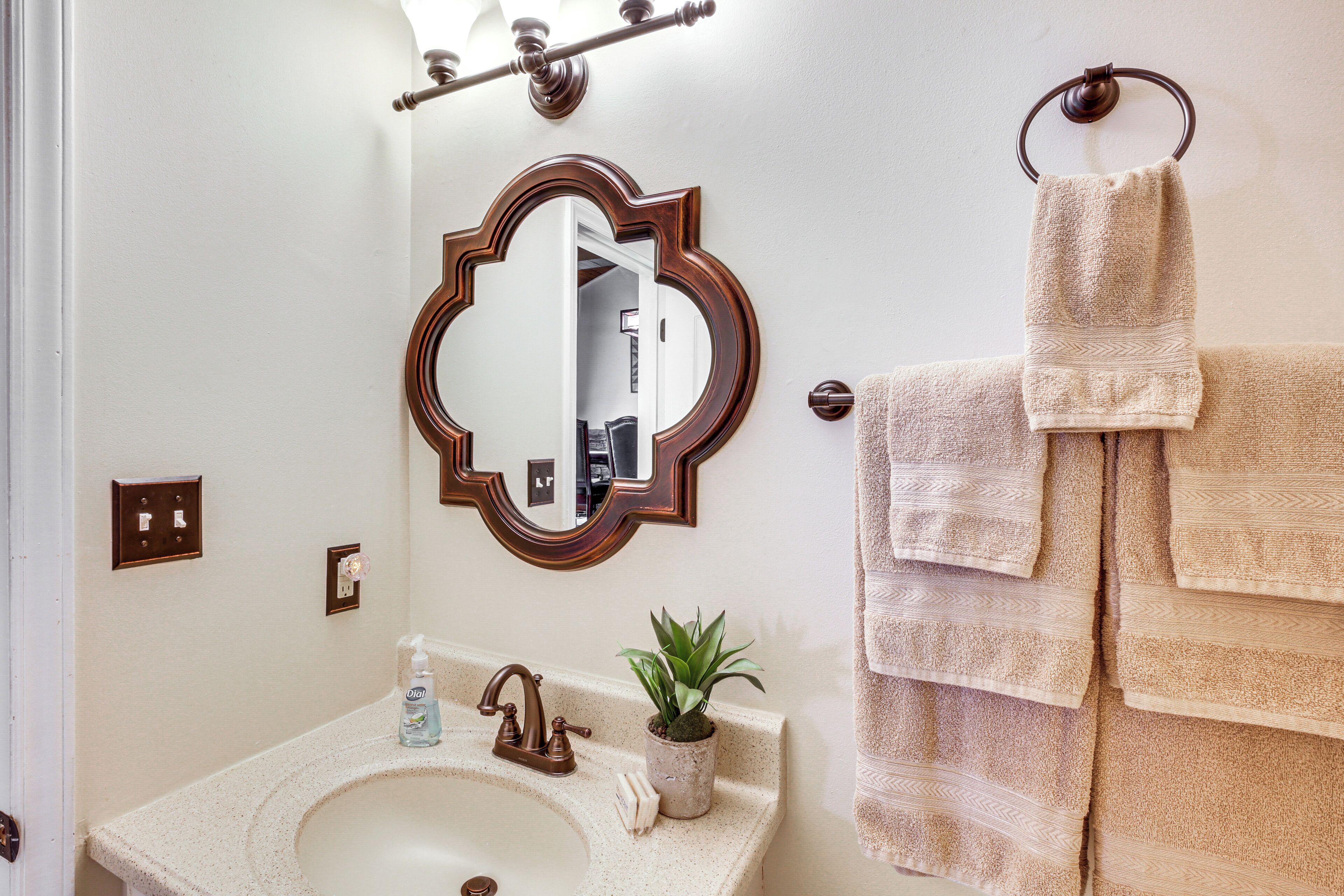 A bathroom with a sink, mirror, towel rack, and a potted plant.