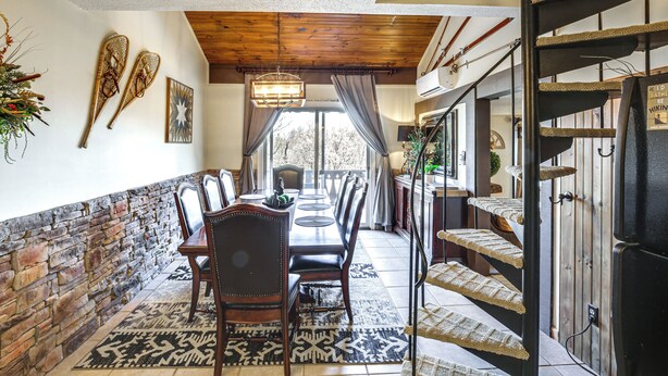 Un comedor con una mesa larga, sillas y un tapete estampado.