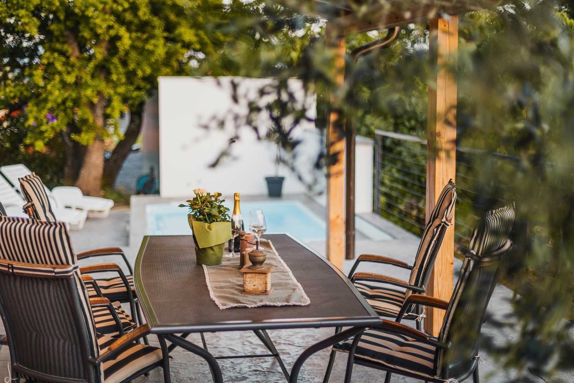 Een terras met een tafel, stoelen en een kleine tuin.