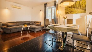 A modern living room with a sofa, dining table, chairs, and a small side table. - Villa Lutoma-2 BD villa with pool and playground (Umag)
