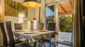 A dining area with a table set for four, a vase with flowers, and a painting on the wall. - Villa Lutoma-2 BD villa with pool and playground (Umag)