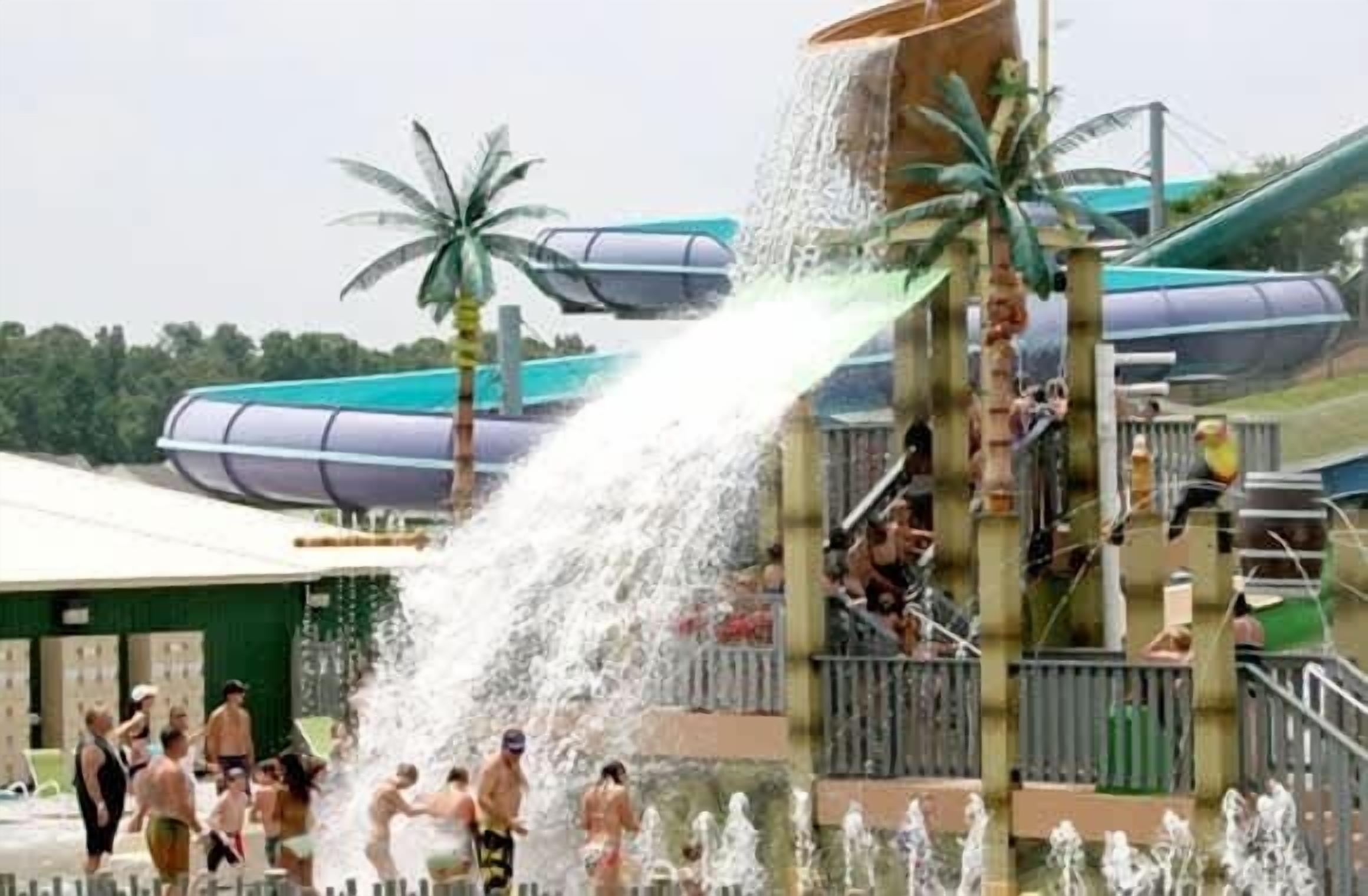 A water park with multiple water slides and a crowd of people enjoying the facilities.