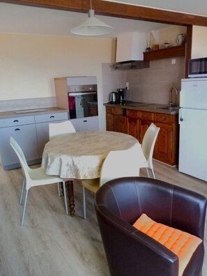 A compact kitchen with a dining area, including a table with chairs, a refrigerator, and a microwave.