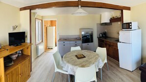 A compact kitchen with a dining table, chairs, a refrigerator, a microwave, and a stove.