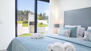 Un dormitorio moderno con una cama grande, vistas a un jardín y una zona de patio.