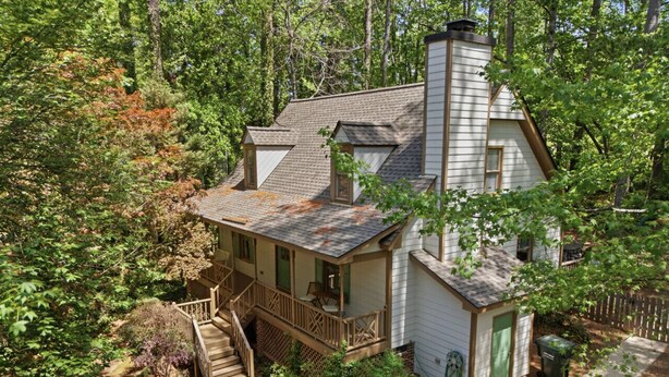 A two-story house with a wooden deck, a chimney, and a small attached garage. - Charming 4BR ★ Family-Friendly ★ w/Backyard ★ (Raleigh)