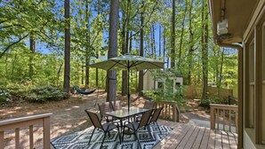 A deck with a table and chairs, surrounded by trees. - Charming 4BR ★ Family-Friendly ★ w/Backyard ★ (Raleigh)