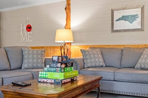 A living room with a sofa, a lamp, and a coffee table with board games.