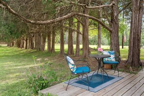 A deck with a table and chairs, surrounded by trees.