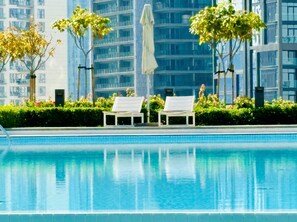 A swimming pool with two white lounge chairs and a statue in the background. - Spectacular Burj Khalifa View Dubai Mall (Dubai)