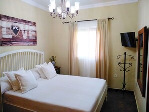 Relax in a stylish room with a large bed, decorative wall piece, and elegant chandelier.