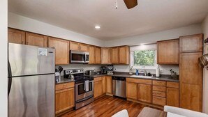 Una cocina moderna con armarios de madera, electrodomésticos de acero inoxidable y piso de madera.