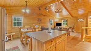 A log cabin interior with a large kitchen island, dining area, and a living room with a fireplace. - Stargazing Dome Cabin W/ Hot Tub , Sauna, Firepit (Logan)