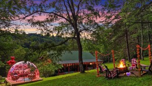 A rustic cabin with a glass dome structure, a fire pit, and string lights. - Stargazing Dome Cabin W/ Hot Tub , Sauna, Firepit (Logan)