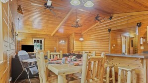 A wooden cabin interior with a dining area, kitchen, and a wheelchair-accessible table. - Stargazing Dome Cabin W/ Hot Tub , Sauna, Firepit (Logan)