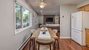 Una cocina moderna con una mesa de comedor, electrodomésticos blancos y un ventilador de techo.