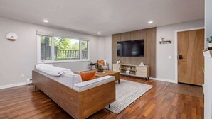 Una sala de estar moderna con un sofá de madera, un televisor de pantalla plana y un mueble de madera.