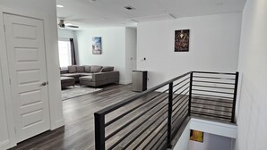Un intérieur moderne comprenant un escalier, un plancher en bois, un espace de vie avec un canapé et une porte.