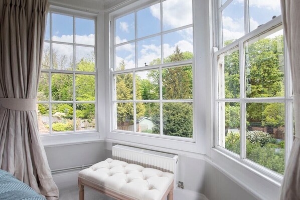 A room with large windows, a radiator, and a tufted bench.