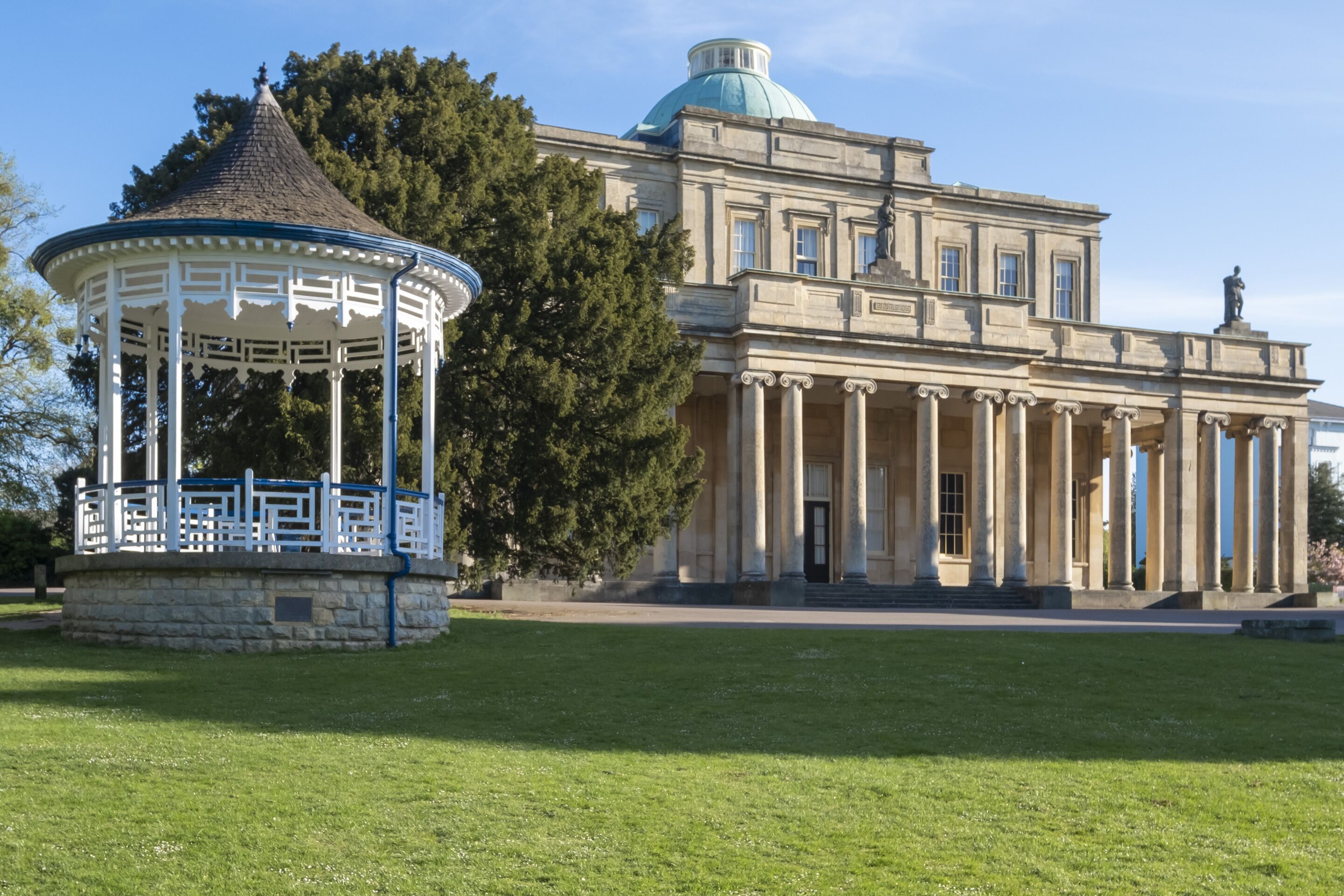 A large building with a dome and columns, a gazebo, and a well-maintained lawn.