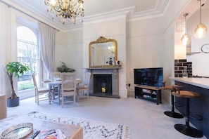 Una sala de estar con chimenea, televisor y comedor con sillas y mesa.