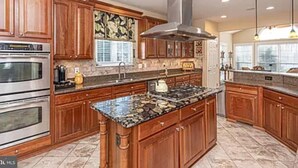 A spacious kitchen with wooden cabinets, granite countertops, stainless steel appliances, and a central island.