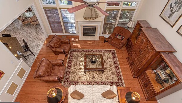 A spacious living room with leather sofas, a patterned rug, a fireplace, and a ceiling fan.