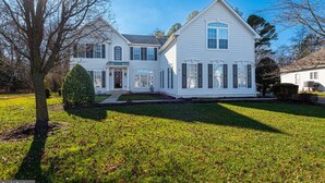 A large, two-story white house with a symmetrical facade, a central entrance, and a well-maintained front yard.