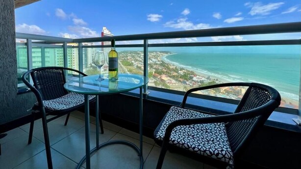 A balcony with two chairs and a table, overlooking a coastal view. - Duna Barcane Vista Mar Pontanegra Natal (Natal)