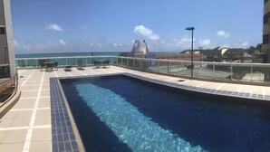 A rooftop pool with a clear view of the ocean and a distant building. - Duna Barcane Vista Mar Pontanegra Natal (Natal)
