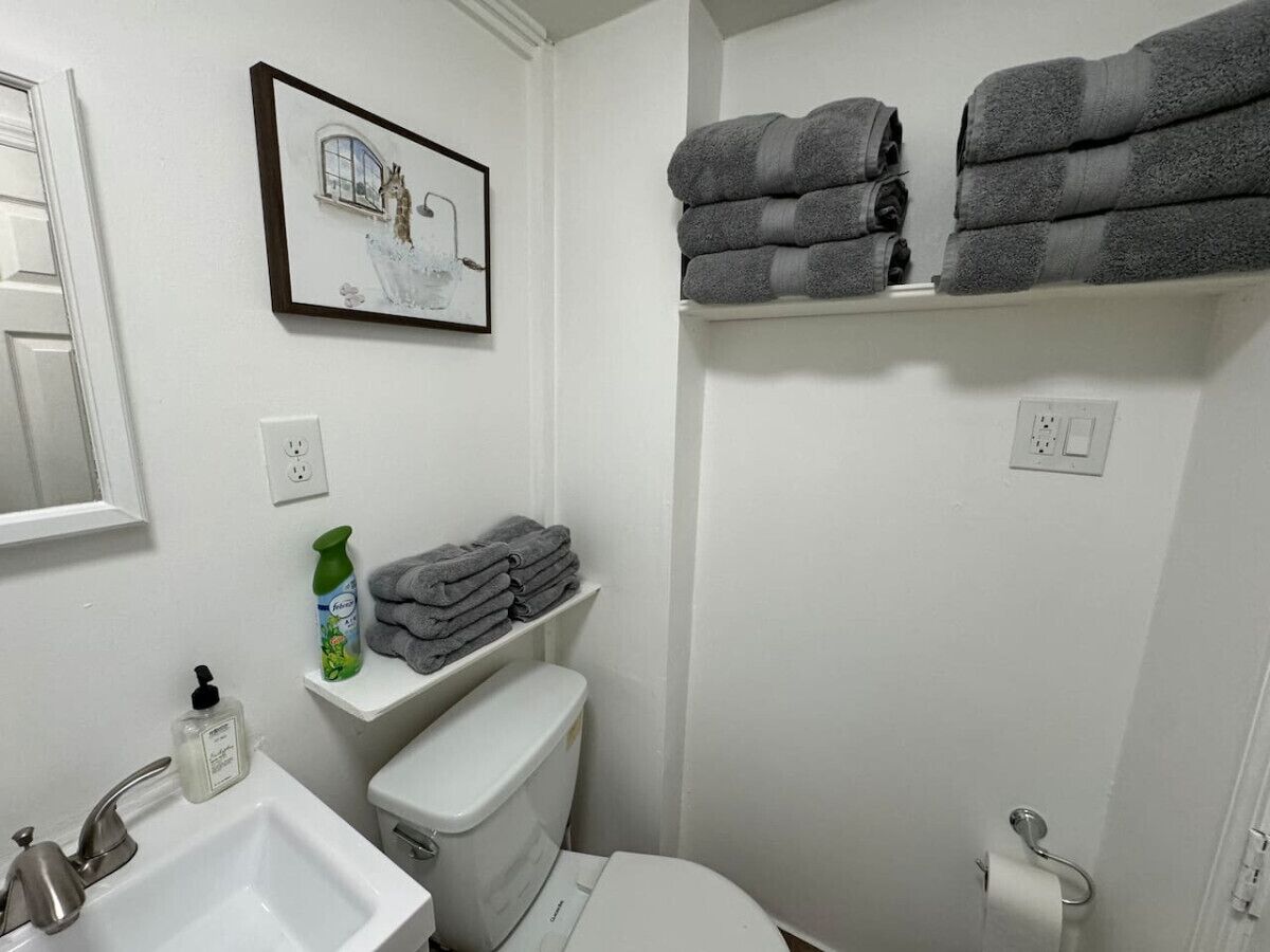 Un baño con inodoro, lavamanos y toalleros.